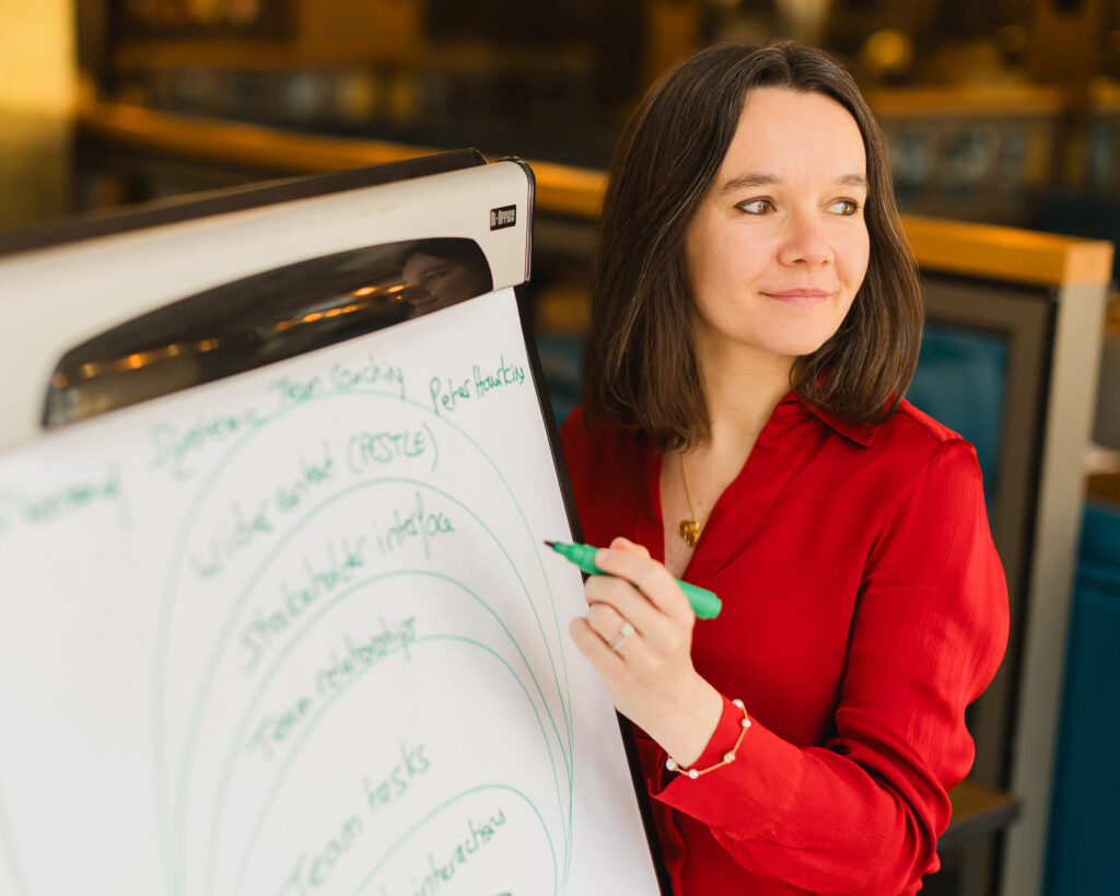 Laurence Galland standing by a flipchart with a pen in hand, listening to a comment with a subtle smile