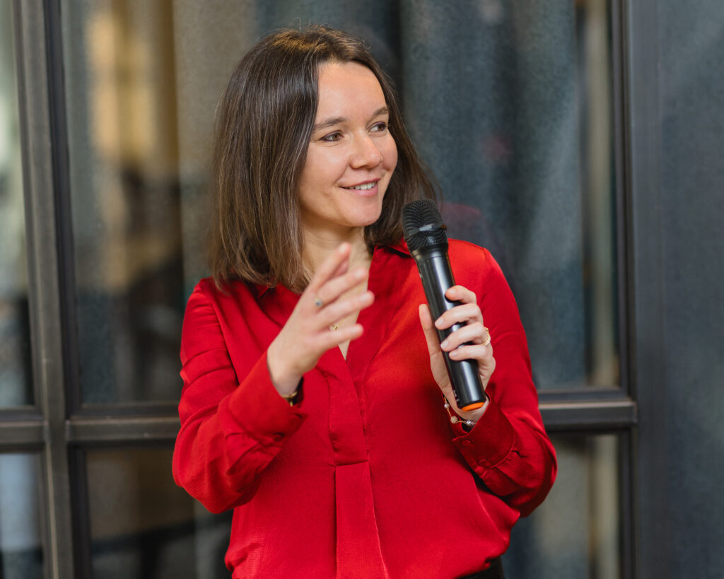 Laurence Galland speaking at a conference, gesturing with one hand while holding a microphone